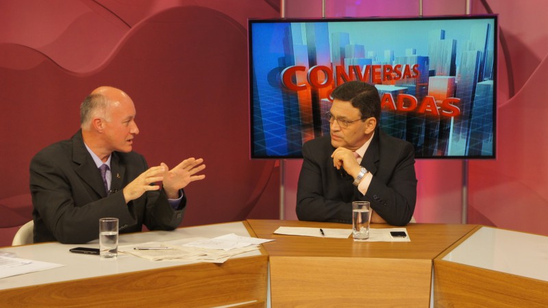 No estúdio do programa Conversas Cruzadas da TV Com,  o presidente da Faders, Roque Bakof, sentado na bancada  falando sobre acessibilidade e ao lado o apresentador Cláudio Brito. Crédito: Aline Puthin.