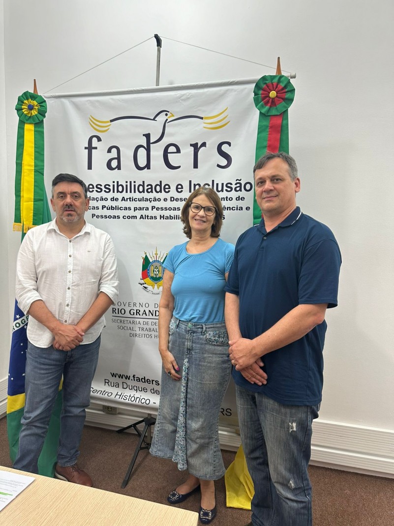 foto - no fundo parede branca, a frente um banner da Faders onde aos lados estão , no esquerdo a bandeira do Brasil e na direita a bandeira do RS, em frente e em pé da esquerda para a direita está o secretário de Trabalho de Marau, a coordenadora de Capacitação e o chefe de gabinete da Faders